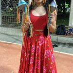 A woman wearing a red dress and holding a pair of colorful kites.