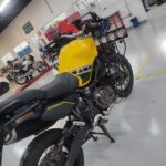 A yellow motorcycle is parked in a garage.