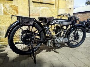 An old motorcycle is parked on a brick walkway.