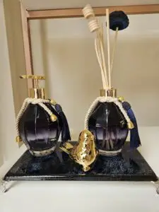 Two bottles of perfume sit on a table, with a bird figurine between them.